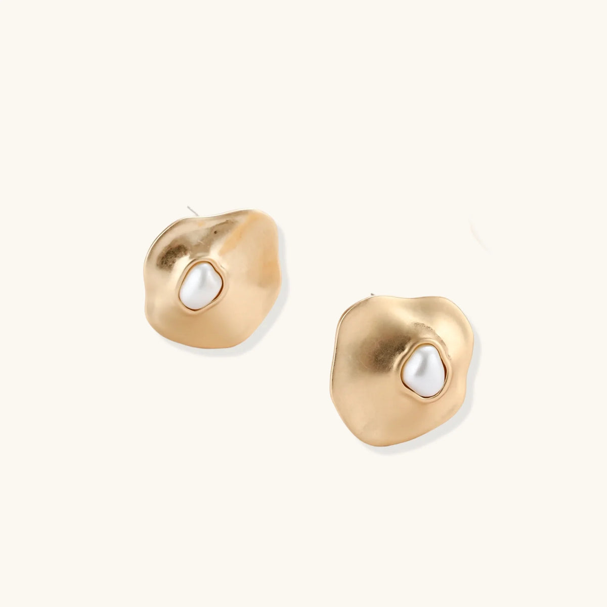 Gold organic-shaped stud earrings with white pearl centers and flowing curves on neutral background.
