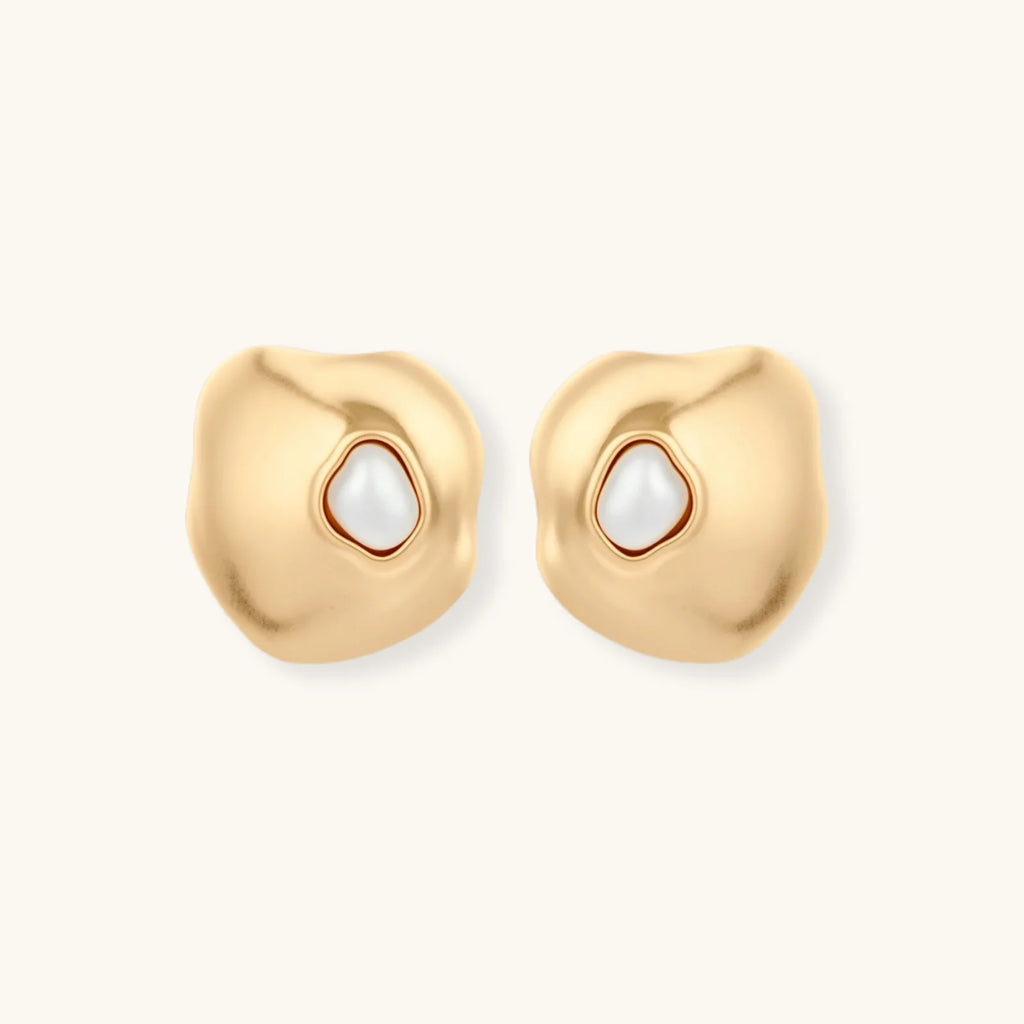 Gold organic-shaped stud earrings with white pearl centers and flowing curves on neutral background.