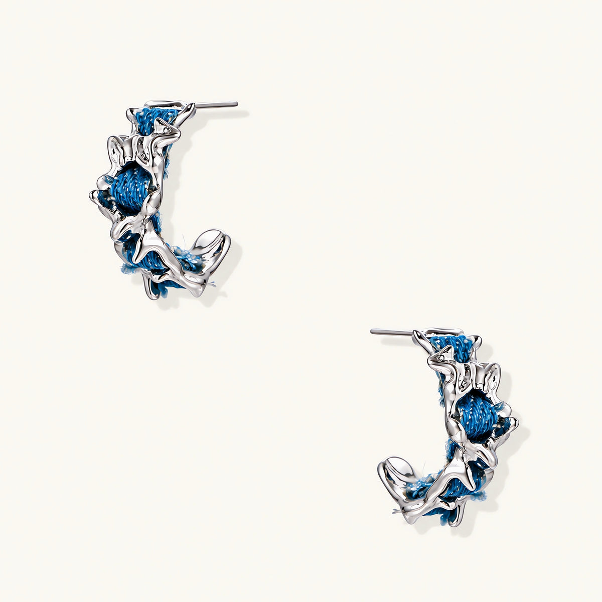 White gold plated hoop earrings with woven blue denim fabric through organic branch-like metal framework