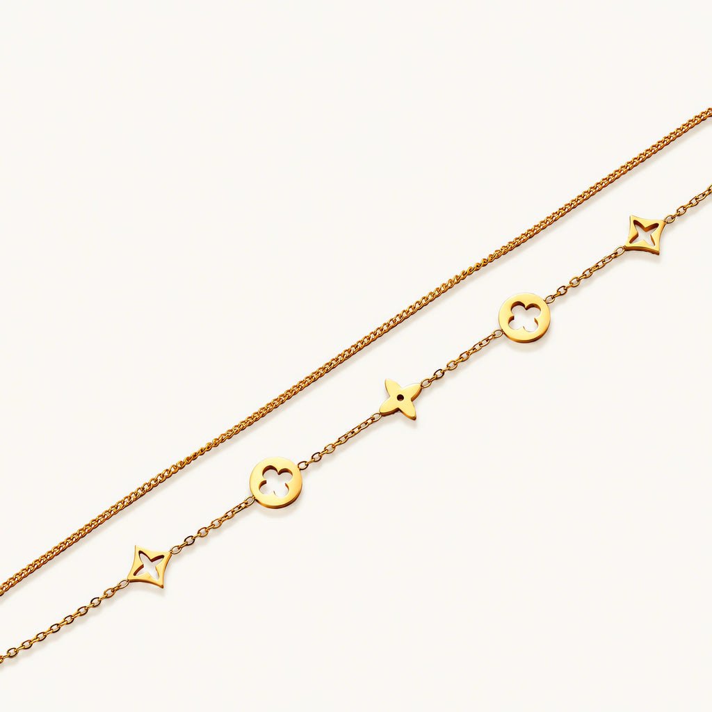Double-layer gold-plated bracelet with quatrefoil and star charms on cream background, 18K gold finish.