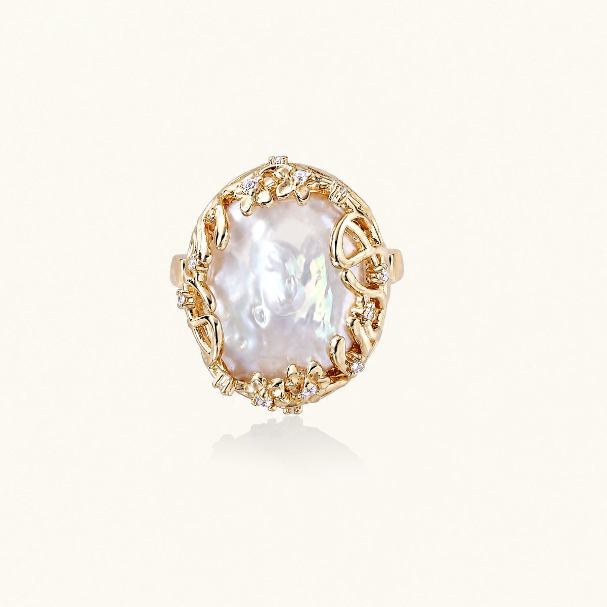Gold filigree crown ring cradling an iridescent baroque freshwater pearl with crystal accents on white background