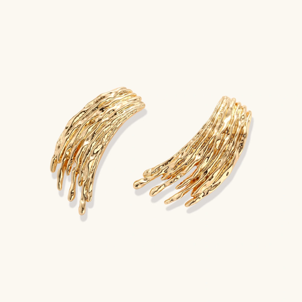 Gold-toned statement earrings with cascading liquid metal-inspired strands on white background.